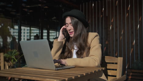 mujer trabajando en una computadora portátil en un café al aire libre