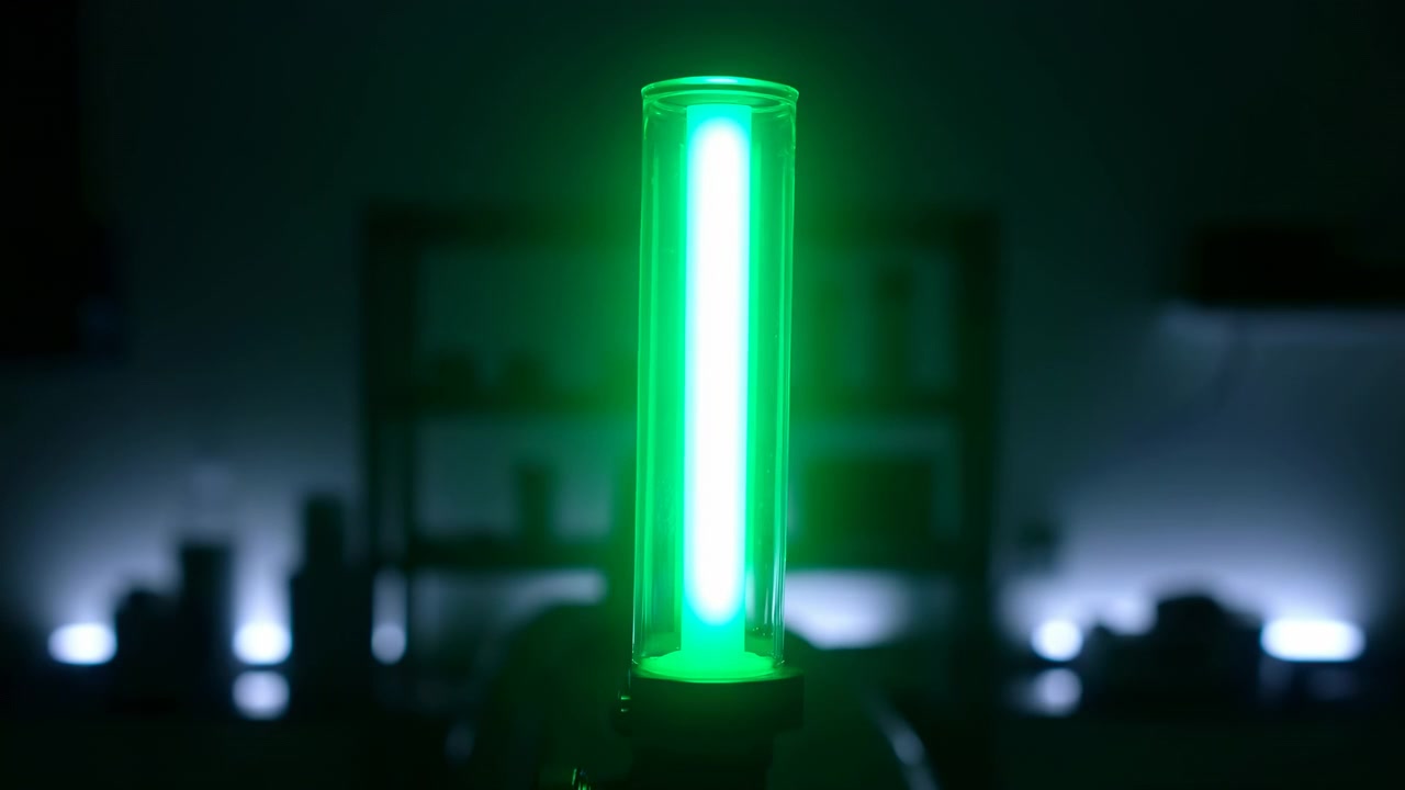 a steady illuminated green light tube in a dim indoor environment with silhouetted figures in the background, creating a mysterious and atmospheric mood, captured in a static shot from alow.