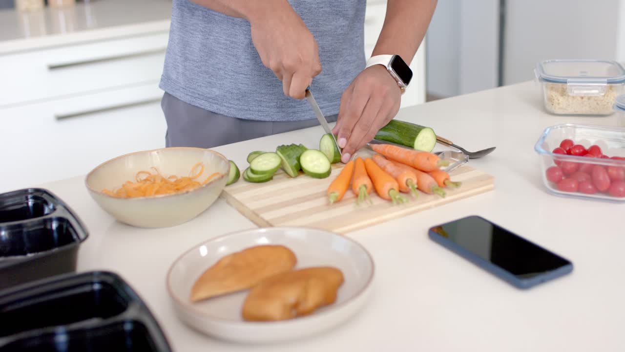 Adult picking up chef's knife at kitchen counter, slicing zucchini into rounds for meal prep