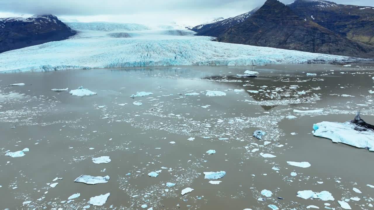 Massive icebergs drifting and melting in dark waters surrounding Vatnajokull glacier, revealing dramatic impacts of climate change in pristine Icelandic landscape
