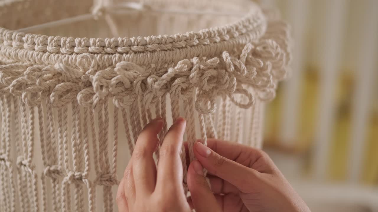 집에서 마크라메를 뜨개질하는 취미. 여성의 손은 두꺼운 가닥으로 장식을 뜨개진다.
