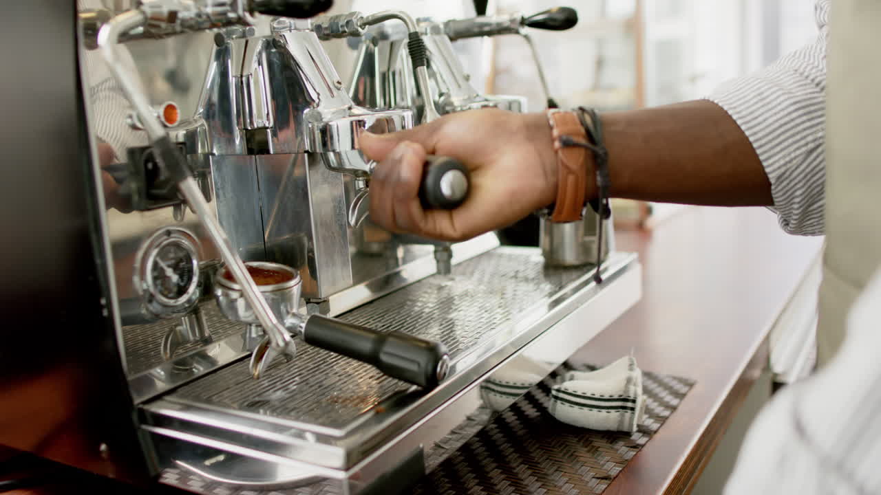 Barista afroamericano che aziona una macchina da caffè espresso, concentrandosi sull'estrazione del caffè