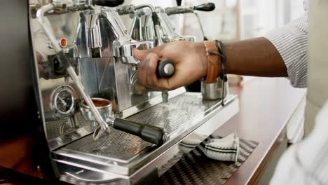 african american barista operates an espresso machine, focusing on the coffee extraction