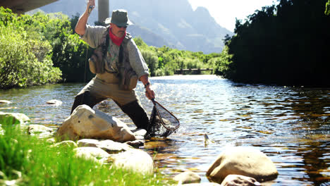fly fisherman catching trout in fishing net