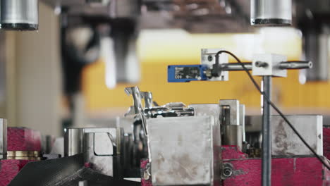 medium shot of a hydraulic press making car parts in the production line, product falling down to the next step in slow motion