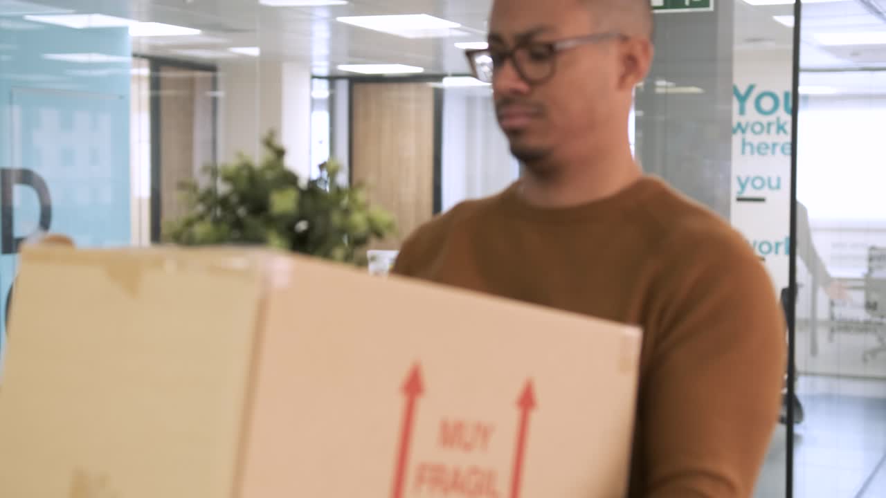 Businessman carrying cardboard box as he leaves creative workspace