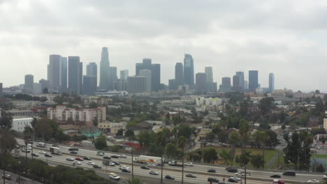 AERIAL:-Echo-Park-towards-Downtown-Los-Angeles,-California-with-Palm-Trees-and-Highway,-Cloudy