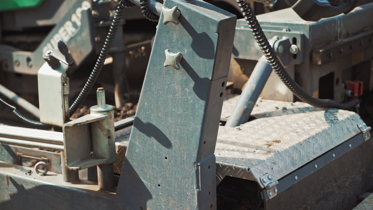 Close-up of a heavy paver machine. Metatal construction of a big machine inside. Asphalt spreader at work. Large truck laying black bitumen.