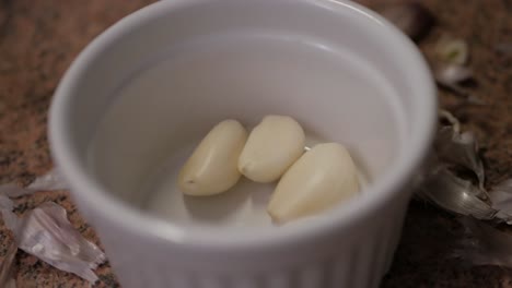 preparing garlic oil by putting the ingredients in a small white cup