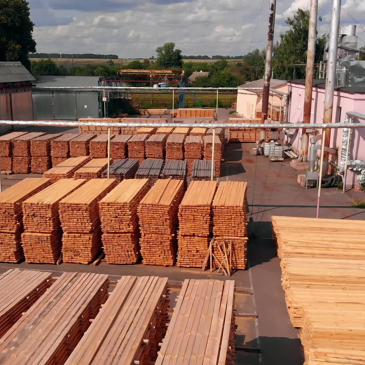 Big stacks of lumber materials stored outdoors. Industrial plant zone for doors making on sunny day