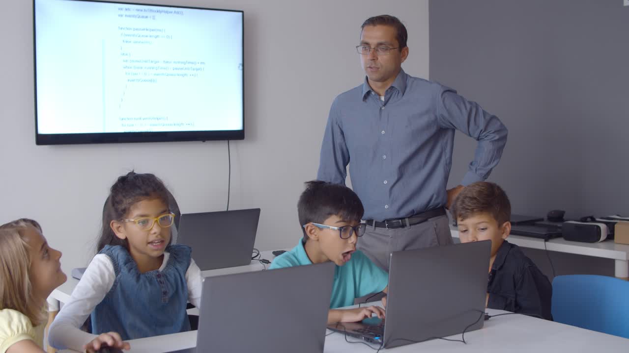 maestro viendo a sus compañeros de clase emocionados usando computadoras portátiles