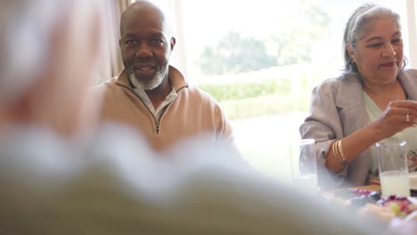 Happy-diverse-senior-male-and-female-friends-serving-food-at-christmas-dinner-table,-slow-motion