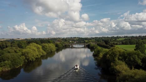 a river boat sailing along the river trent towards a road bridge on a beautiful, bright, sunny, summers day