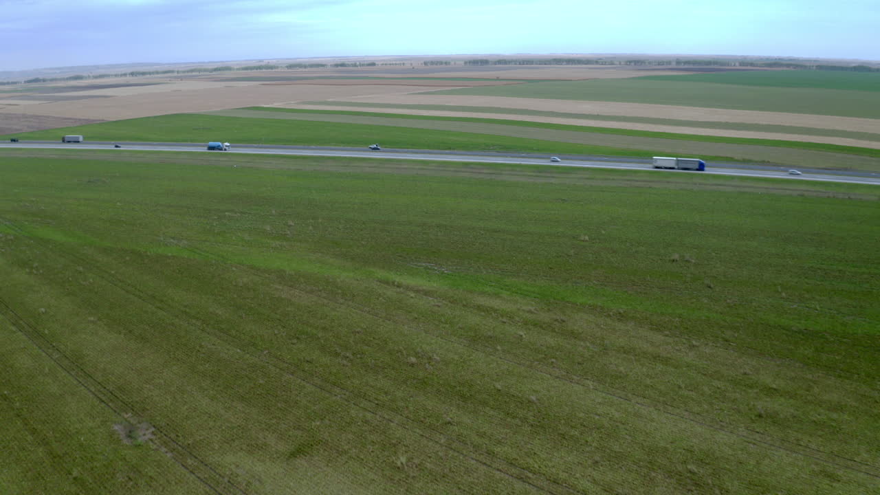 Aerial view of trucks on highway amidst green fields