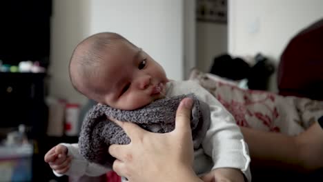 father using towel to gently hold his 2 month old son and rubbing his back as baby's head flops forward