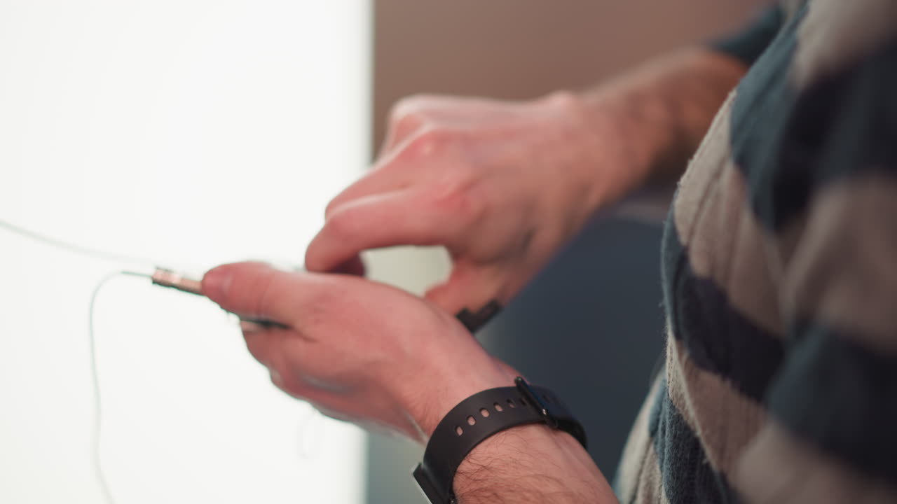 hands male technician connect wireless microphone transmitter cables to bodypack audio unit in studio with blue backdrop lights during live broadcast setup backstage rigging preparation