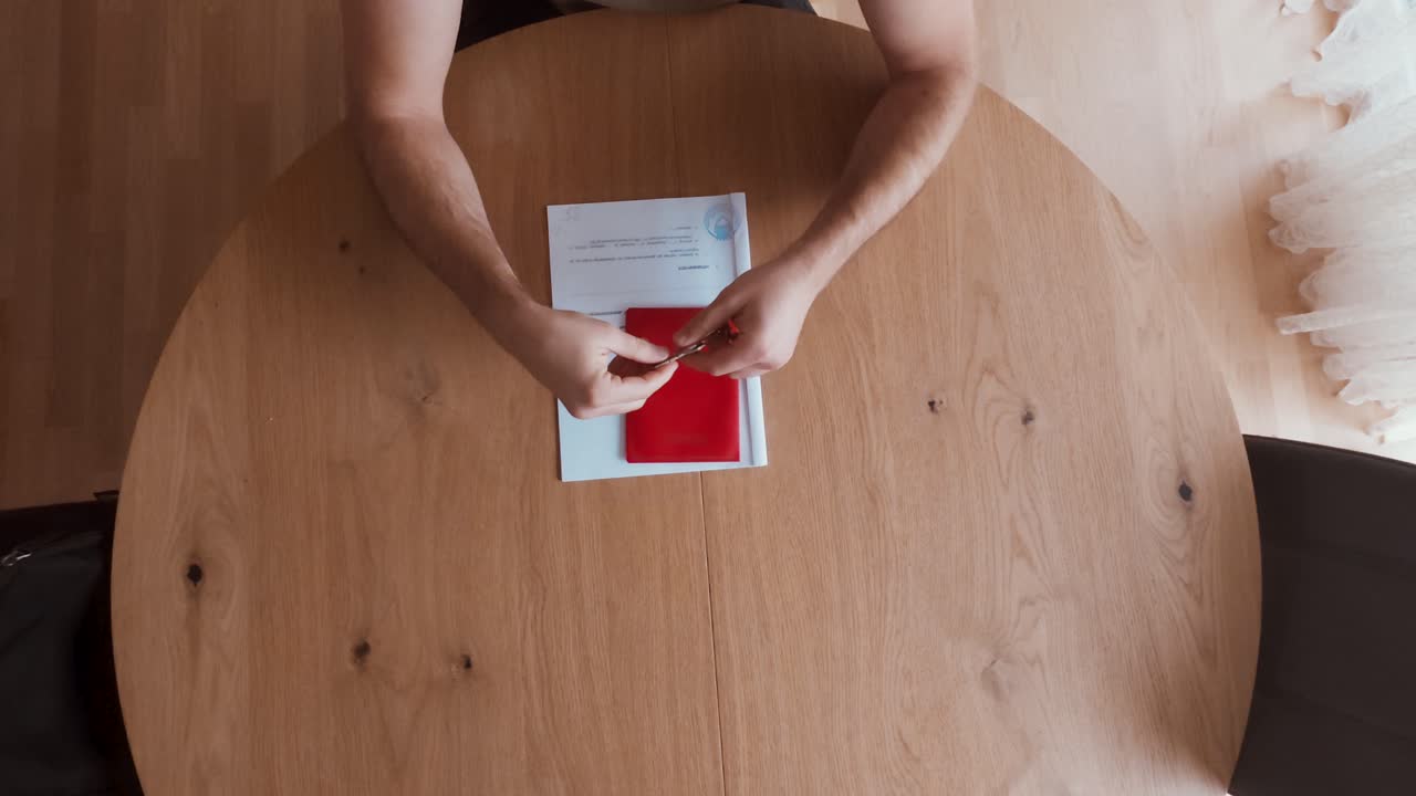 A man sits at a wooden table, explains contract terms, and hands over a red folder containing a rental or purchase agreement. Perfect for real estate, housing, or business negotiation themes