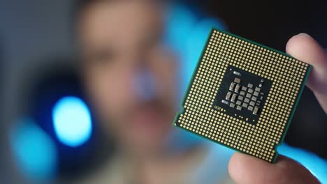 el técnico masculino sostiene en la mano el procesador de la cpu, el concepto de microchips de circuitos integrados, el fondo borroso