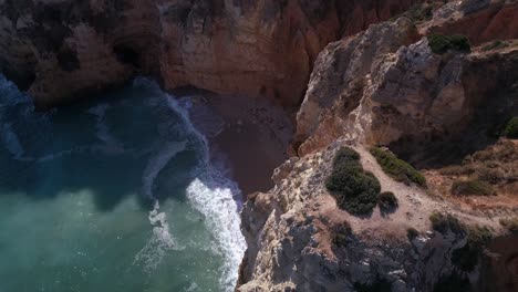 Top down aerial descending amongst cliffs towards a cove near Lagos, Portugal.