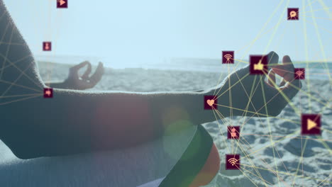 globos de iconos digitales girando contra la sección media de una persona meditando en la playa