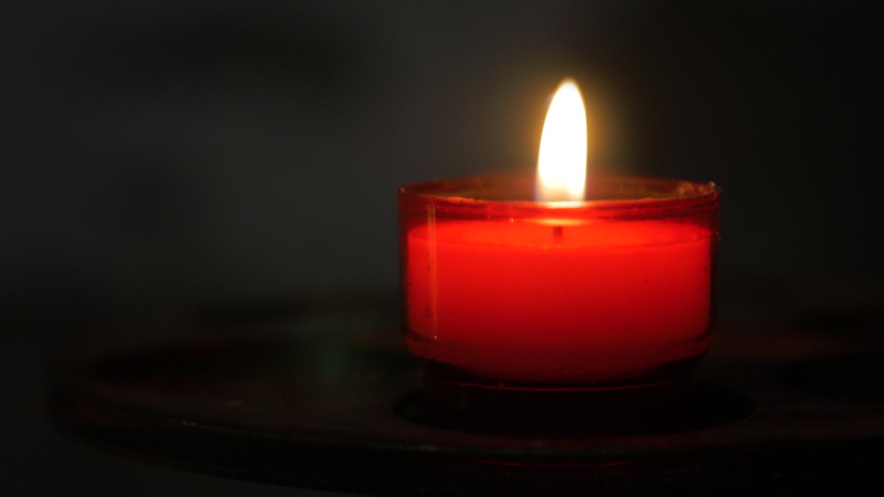 Candela rossa accesa isolata su sfondo nero, che ricorda concetti di religione, amore romantico e festività
