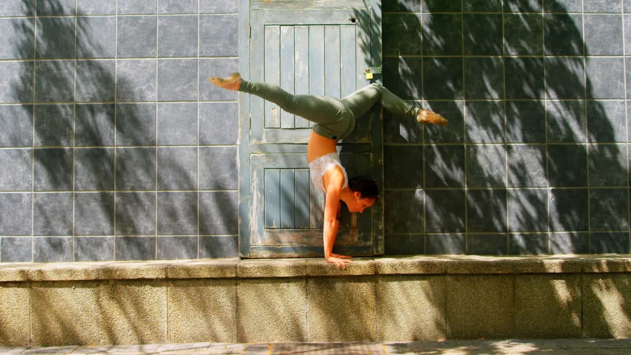 joven bailarina practicando el handstand contra la pared 4k