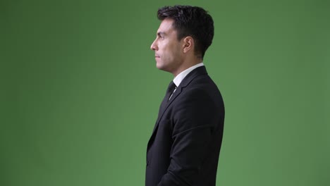 young handsome hispanic businessman against green background