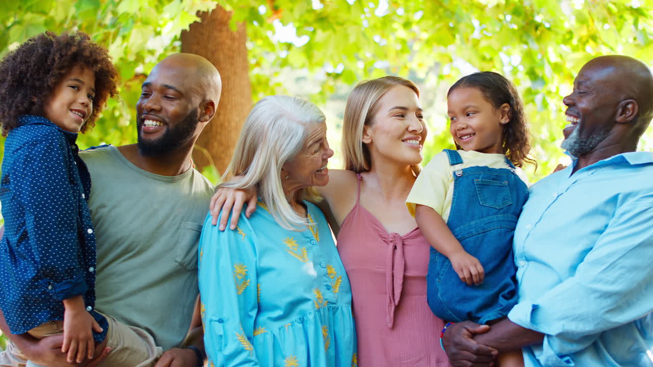 retrato de una familia de varias generaciones de pie en el jardín sonriendo a la cámara