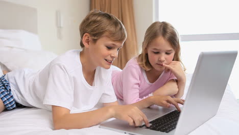 happy siblings using a laptop