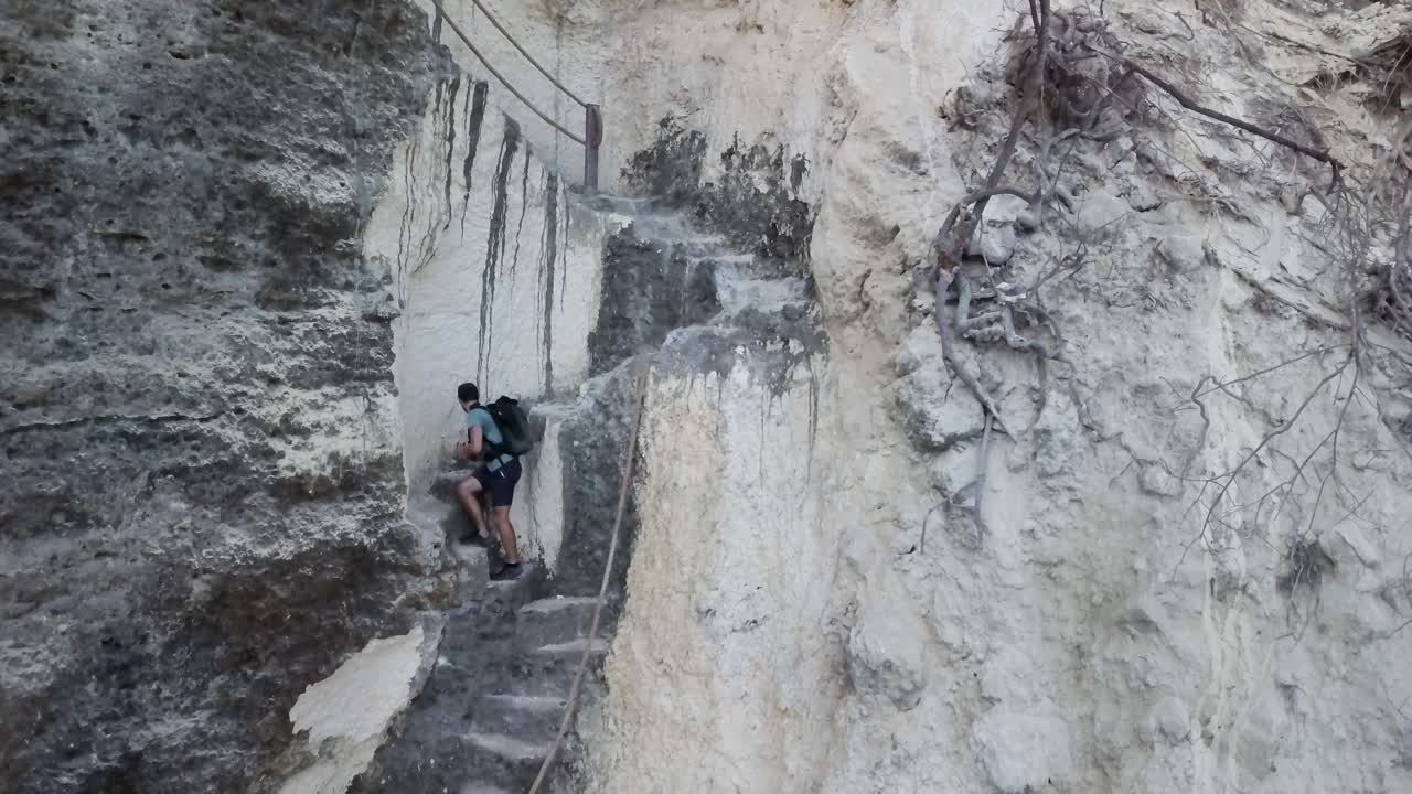 un excursionista sube un conjunto de escalones tallados en un acantilado en un camino costero australiano