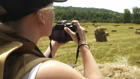 girl hiker takes photos in rural agricultural scene with golden hay bales