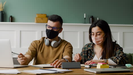 estudiante con auriculares hablando con una compañera en la mesa discutiendo sobre un proyecto usando una laptop 1