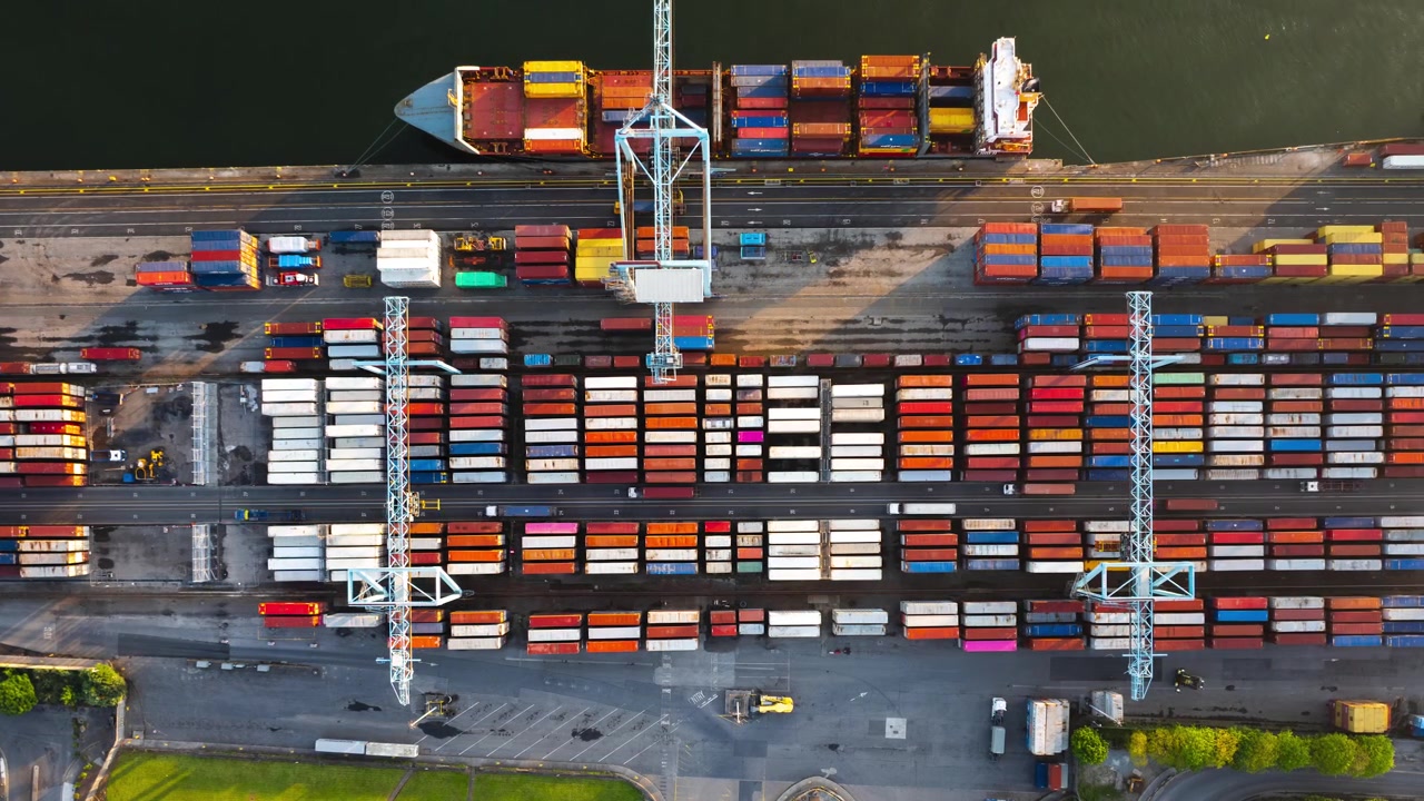 Container cranes lift trailers and freight as a cargo ship is loaded at a busy Irish terminal in fast motion.