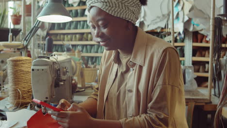 cheerful african american woman messaging on phone in workshop