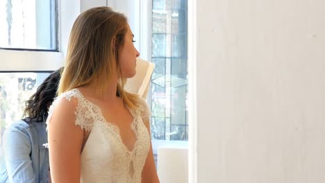 mujer probando el vestido de novia con la ayuda de un diseñador de moda