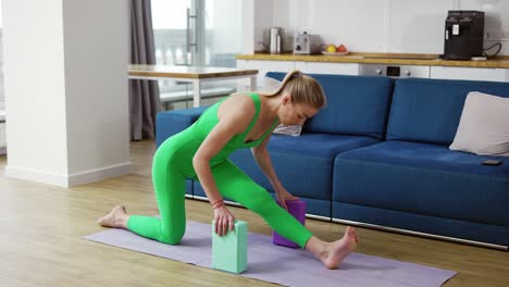 mujer estirando las piernas con bloques de yoga en la sala de estar en casa
