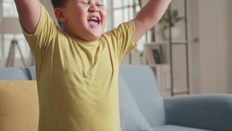 close up of child asian gamer is feeling excited and raising his arms with fist gesture while playing online cyber sport game at home