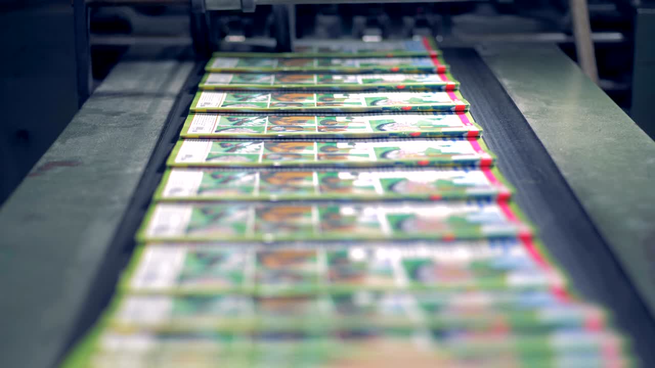 A row of journals is moving along the conveyor belt and getting piled up