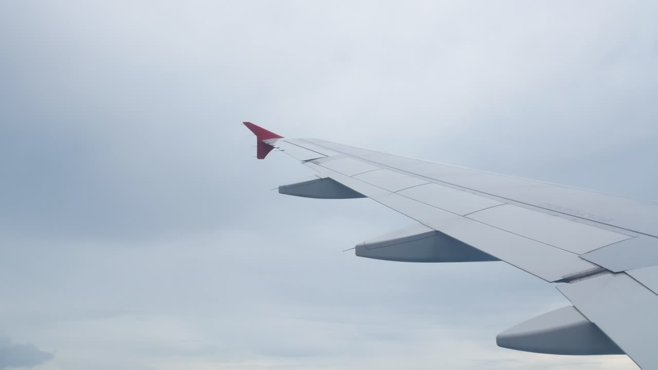 Himmel från flygplan med vinge över moln en sommardag.