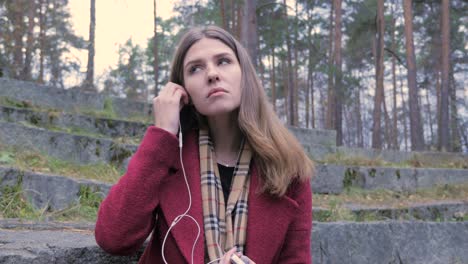 young woman listening to music in a forest