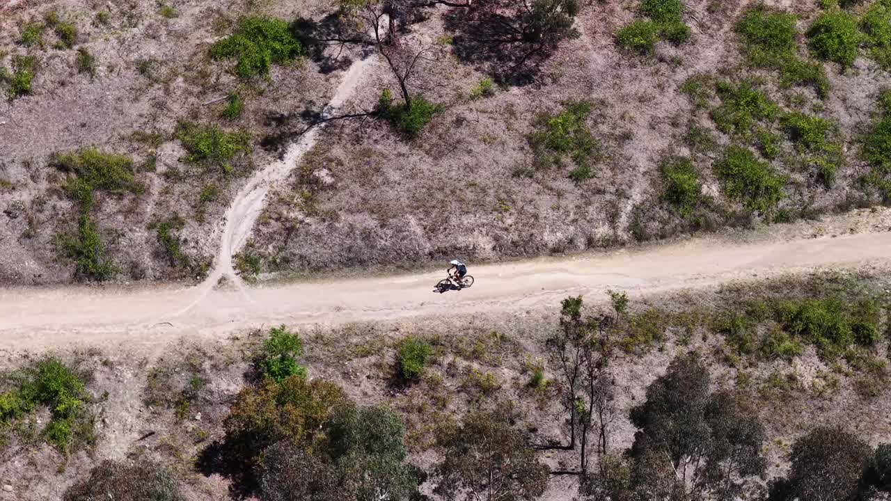 Ripresa aerea dall'alto segue un ciclista che percorre un tortuoso sentiero sterrato per mountain bike