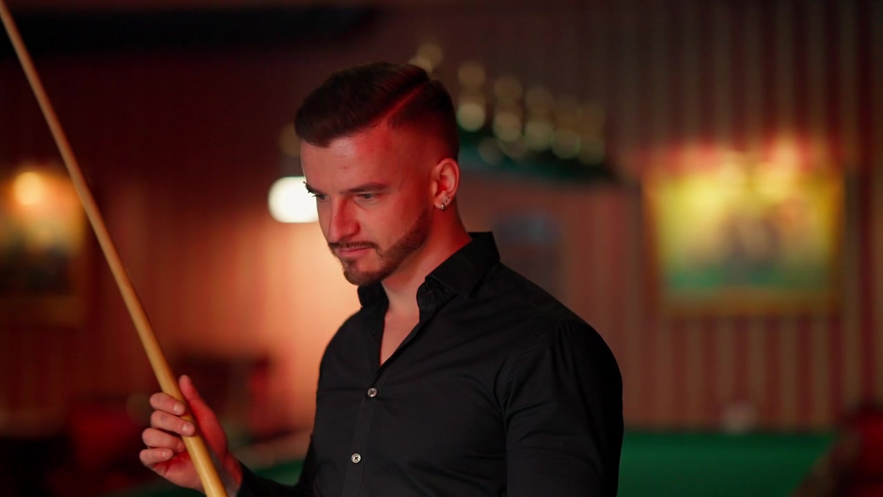 Homme concentré tenant une queue de billard dans une salle de billard