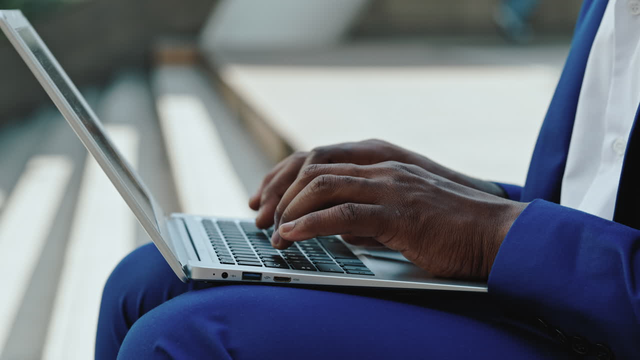 Close-up of a person typing on a laptop outdoors