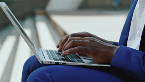 close-up of a person typing on a laptop outdoors