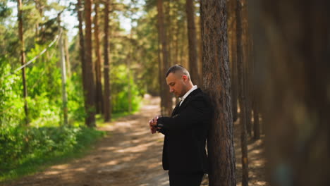 man in suit checks time waiting for girlfriend in forest