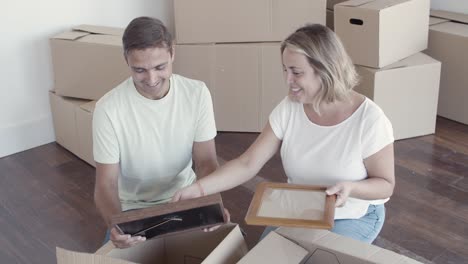 Happy-couple-talking-while-packing-things-for-moving