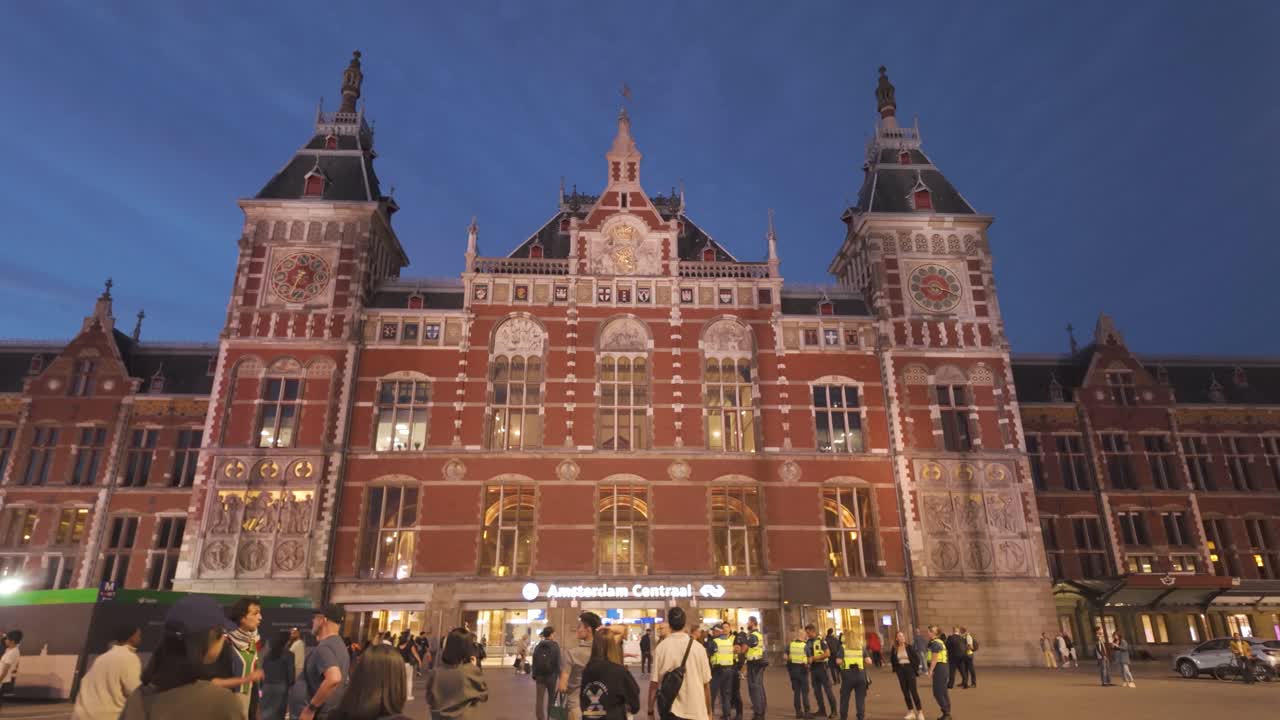 Crowds gather outside Amsterdam Central Station at dusk in the Netherlands