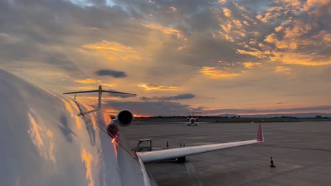 Vista-Superior-Del-Fuselaje-Del-Jet-Justo-Antes-De-La-Puesta-Del-Sol-Con-Un-Hermoso-Cielo-Invernal-Con-El-Cielo-Reflejado-En-El-Avión,-Y-Otro-Avión-Gravando