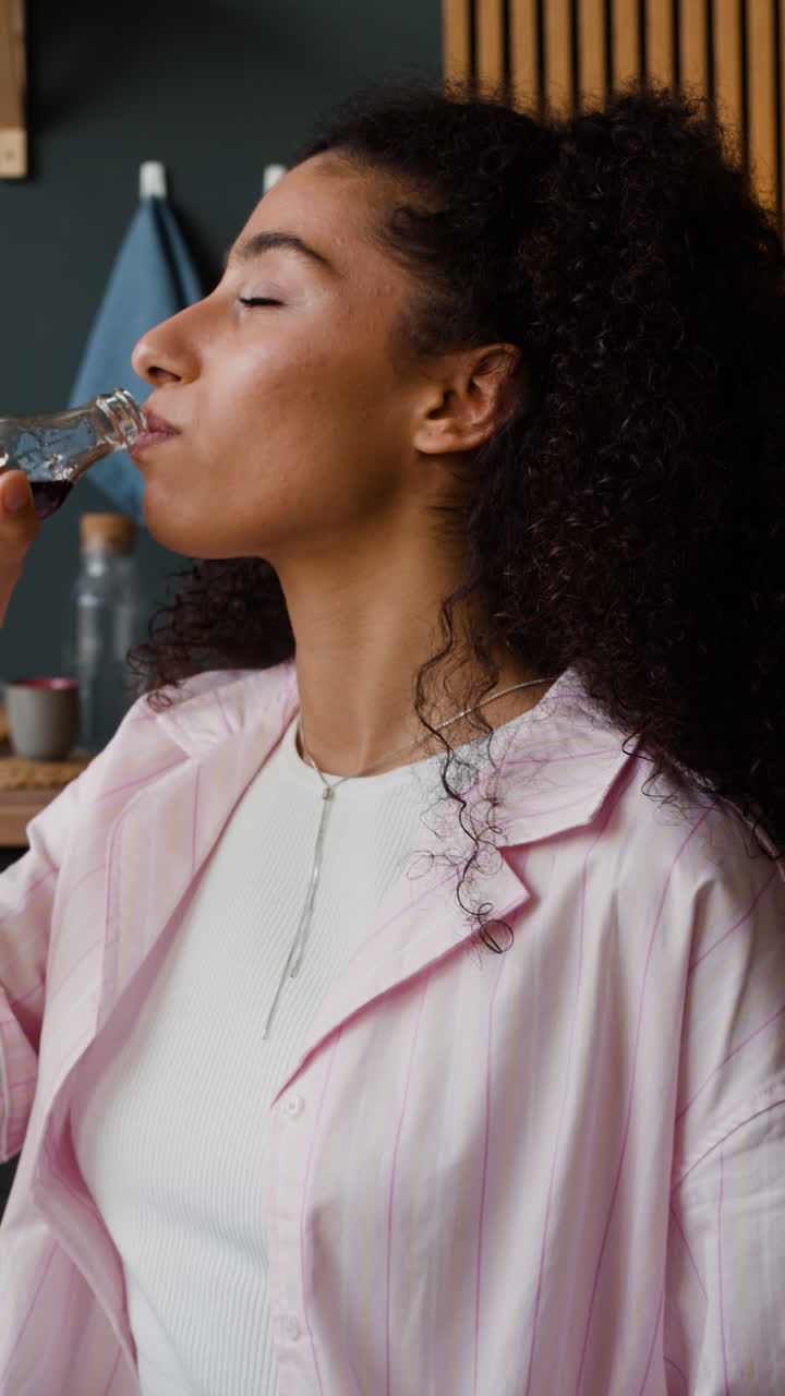 Woman enjoying her morning routine in a home kitchen, with coffee and a drink