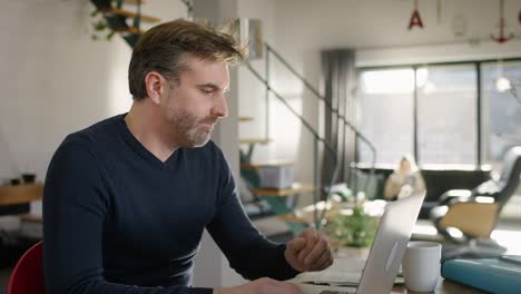 middle aged man looking worried at his laptop at home